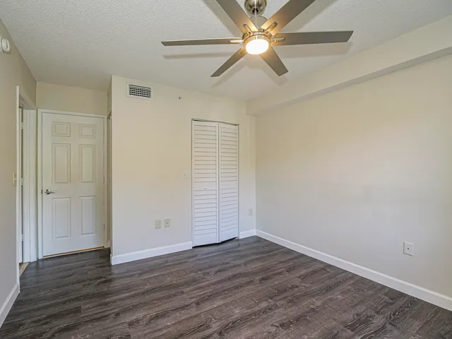 an empty room with wooden floor closet and fan