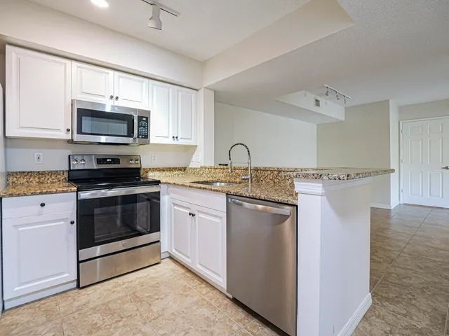 a kitchen with stainless steel appliances granite countertop a stove a sink and a microwave