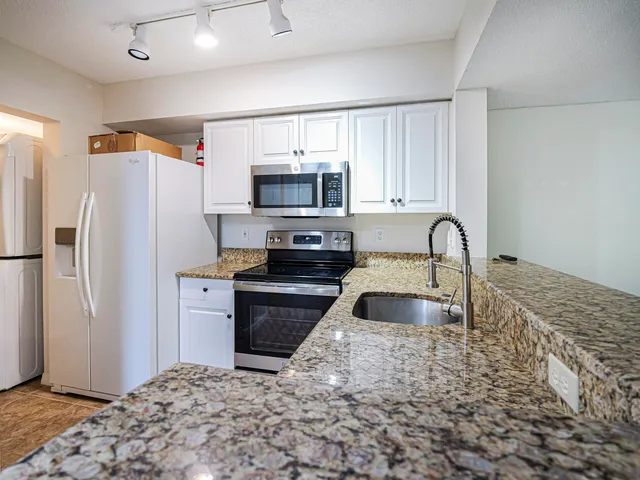a kitchen with granite countertop a refrigerator and a sink