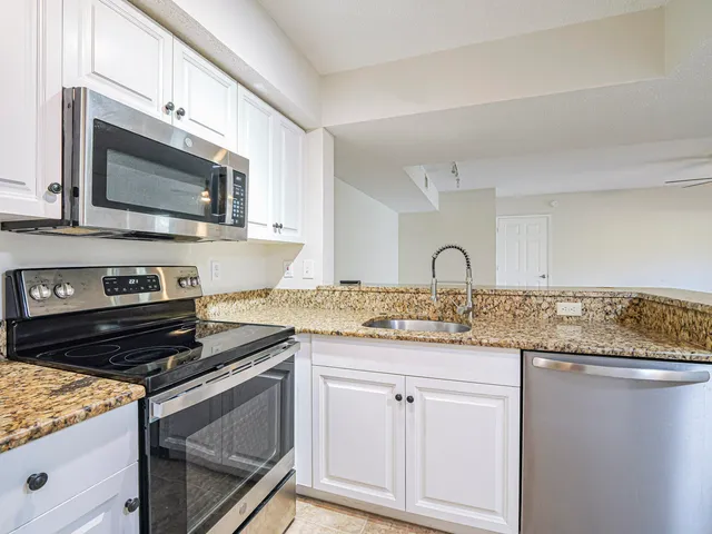 a kitchen with granite countertop white cabinets and appliances