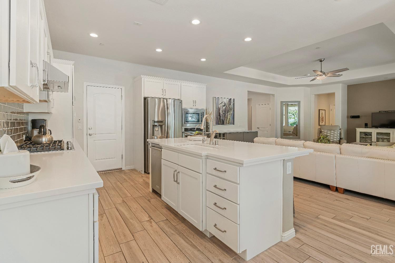 Undisclosed Address Bakersfield, CA 93311 - Photo 10 of 25 a large white kitchen with kitchen island a sink a center island stainless steel appliances and a counter space