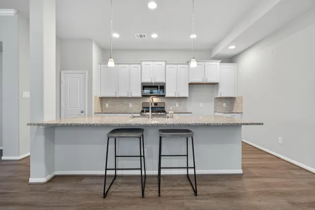 a kitchen with stainless steel appliances granite countertop a stove top oven a sink dishwasher and a refrigerator with wooden floor