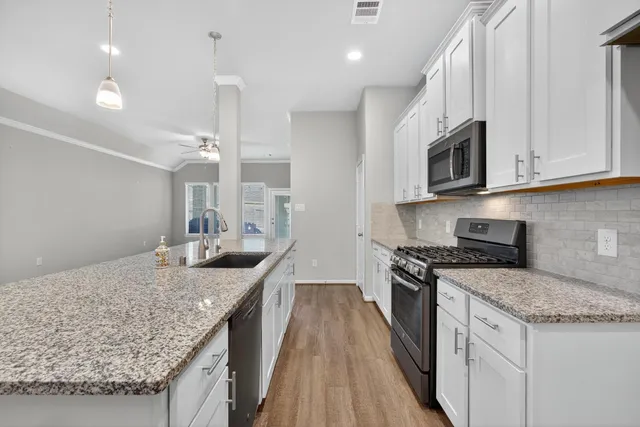 a kitchen with granite countertop a sink and dishwasher with wooden floor