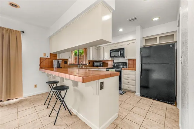 a kitchen with stainless steel appliances kitchen island granite countertop a refrigerator a stove a sink and a microwave