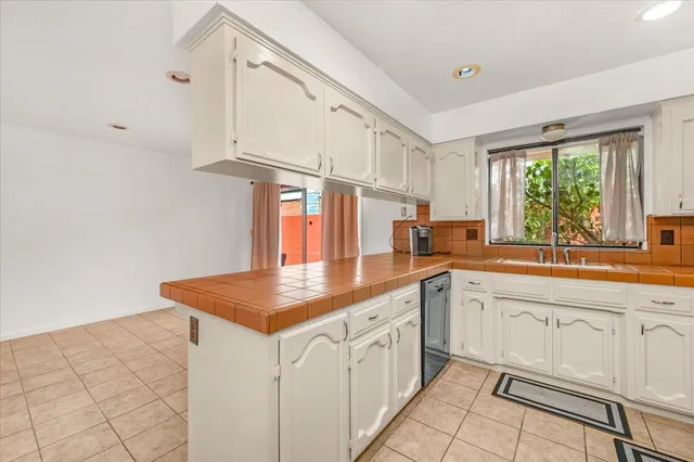 a kitchen with white cabinets a sink dishwasher and a stove with wooden floor
