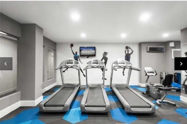 a room with gym equipment and wooden floor