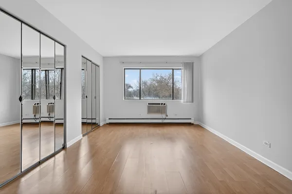 a view of empty room with wooden floor and fan