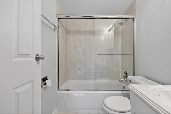 a bathroom with a granite countertop bathtub shower sink vanity and toilet