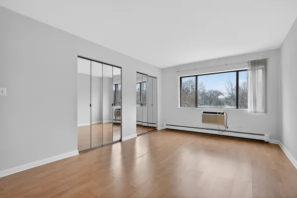 a view of an empty room with a window and wooden floor