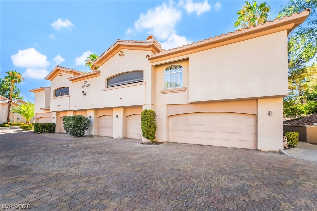 2050 West Warm Springs Road, Unit 2411 Henderson, NV 89014 - Photo 2 of 37 A striking stucco facade with multiple garage doors and a paved driveway creates a welcoming entry.