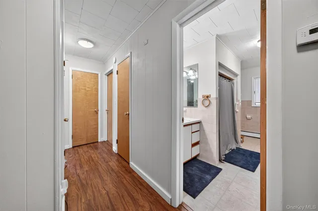 a view of a hallway with wooden floor and a bathroom