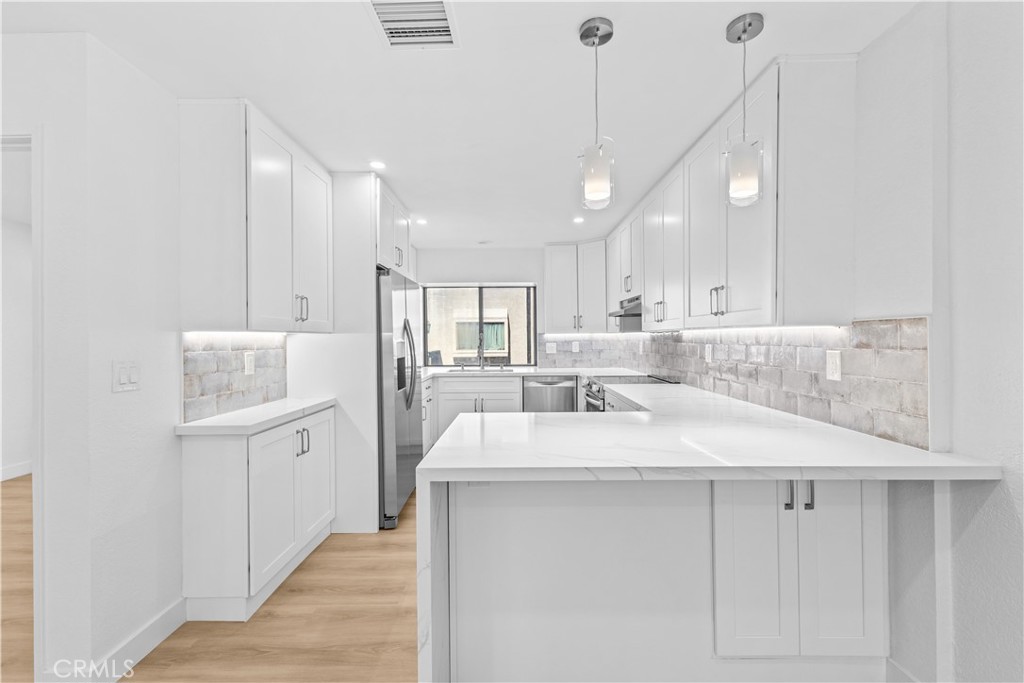 10 Sunshine, Unit 31 Irvine, CA 92603 - Photo 3 of 29 a large white kitchen with kitchen island a sink stainless steel appliances and a cabinets