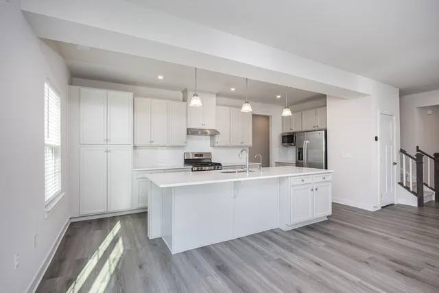 a large white kitchen with kitchen island a sink a stove a refrigerator and white cabinets