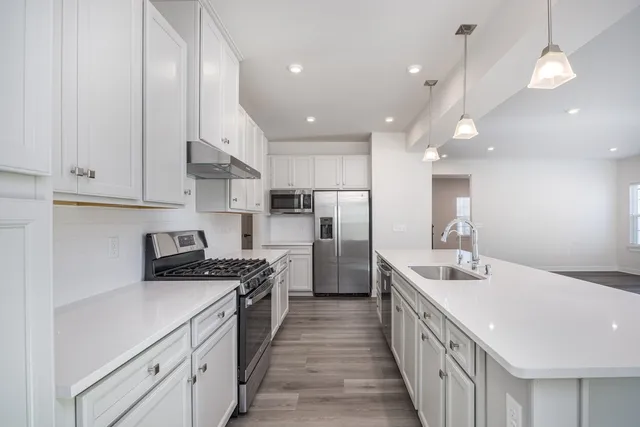 a kitchen with stainless steel appliances granite countertop a sink a stove and a refrigerator