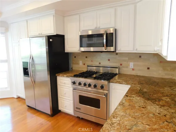 a kitchen with a sink wooden cabinets and a window