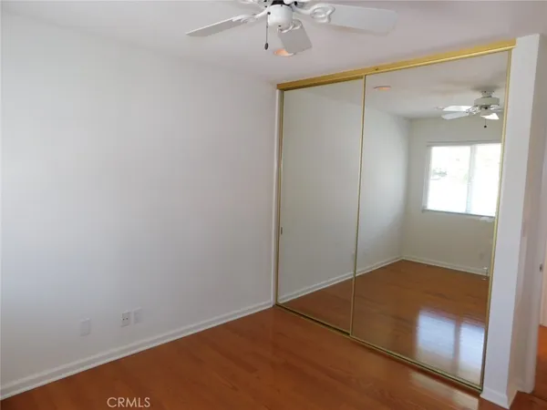 an empty room with a chandelier fan and wooden floor