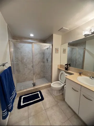 a bathroom with a double vanity sink a toilet a mirror and shower
