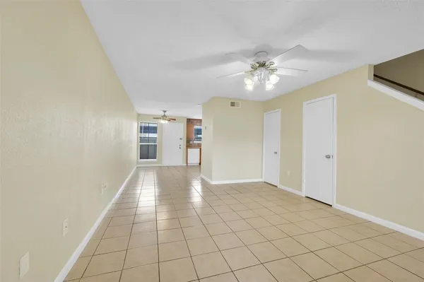 a view of an empty room and chandelier fan