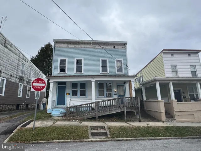 a view of a white house with large windows and a small yard