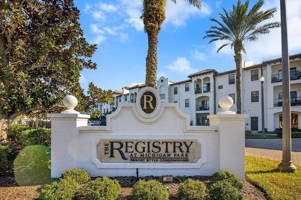 a view of sign board with buildings and trees around