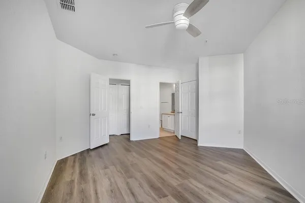 a view of empty room with wooden floor and fan