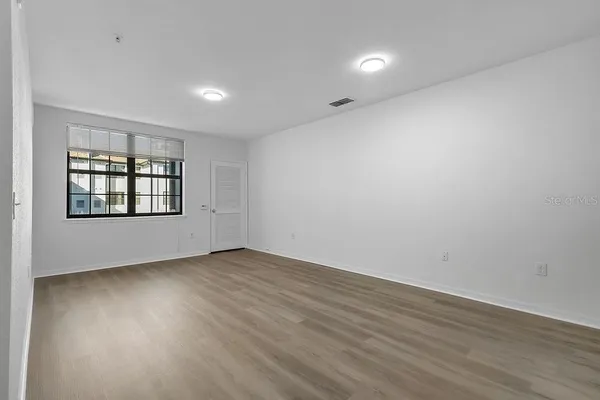 an empty room with wooden floor and windows