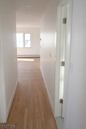 a view of a hallway with wooden floor and a bathroom