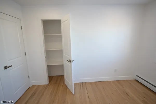 a view of an empty room with wooden floor and closet