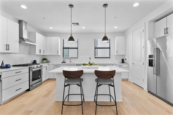 a living room with kitchen island furniture wooden floor and a chandelier