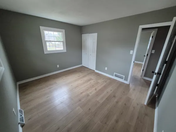 an empty room with wooden floor and windows