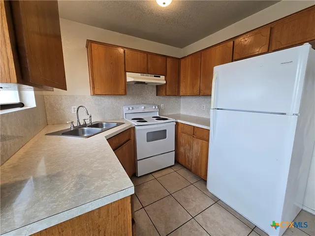 a kitchen with a refrigerator sink stove and cabinets