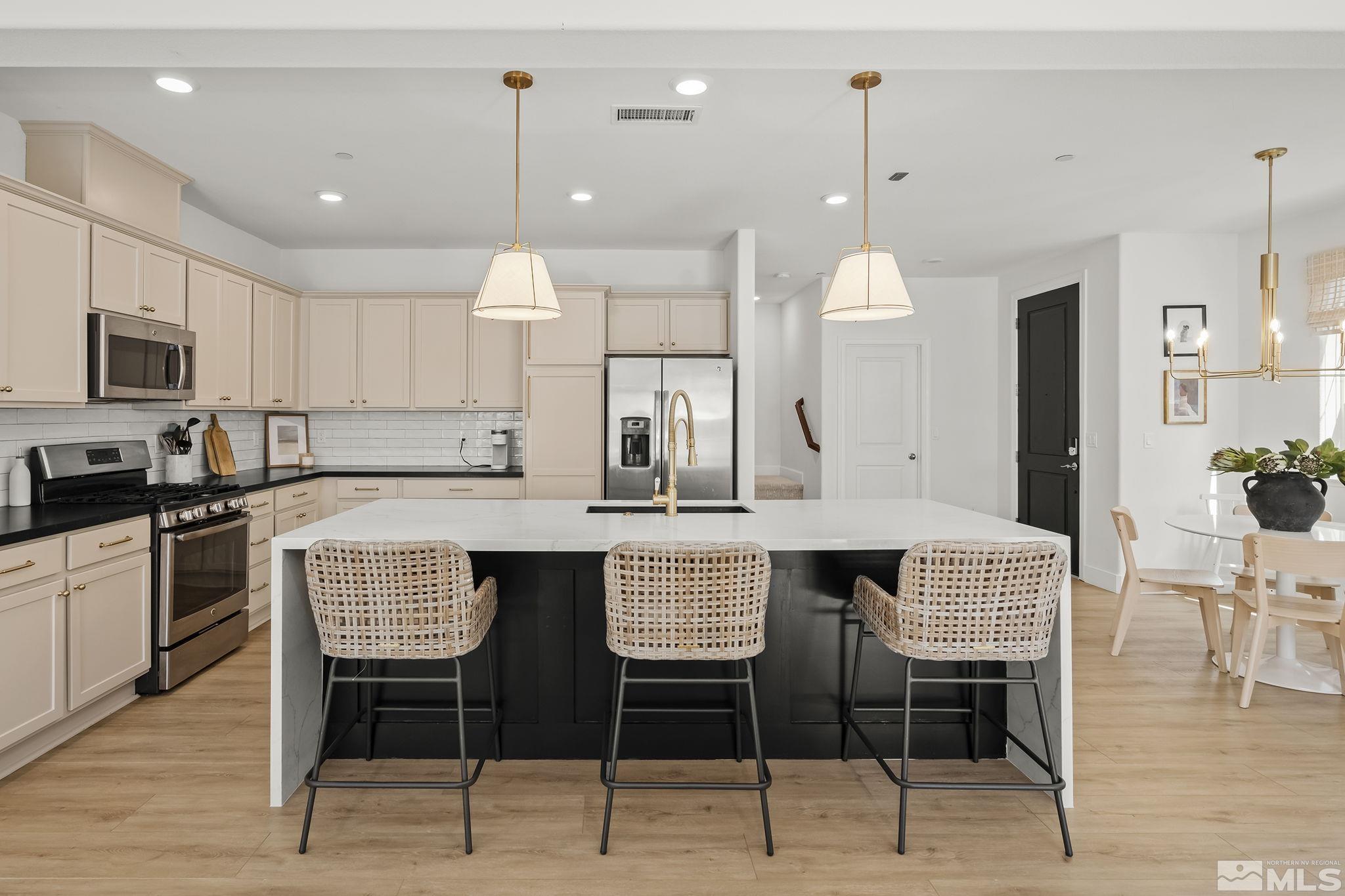 2041 Wind Ranch Road, Unit C Reno, NV 89521 - Photo 7 of 27 a kitchen with stainless steel appliances kitchen island granite countertop a dining table chairs and a refrigerator