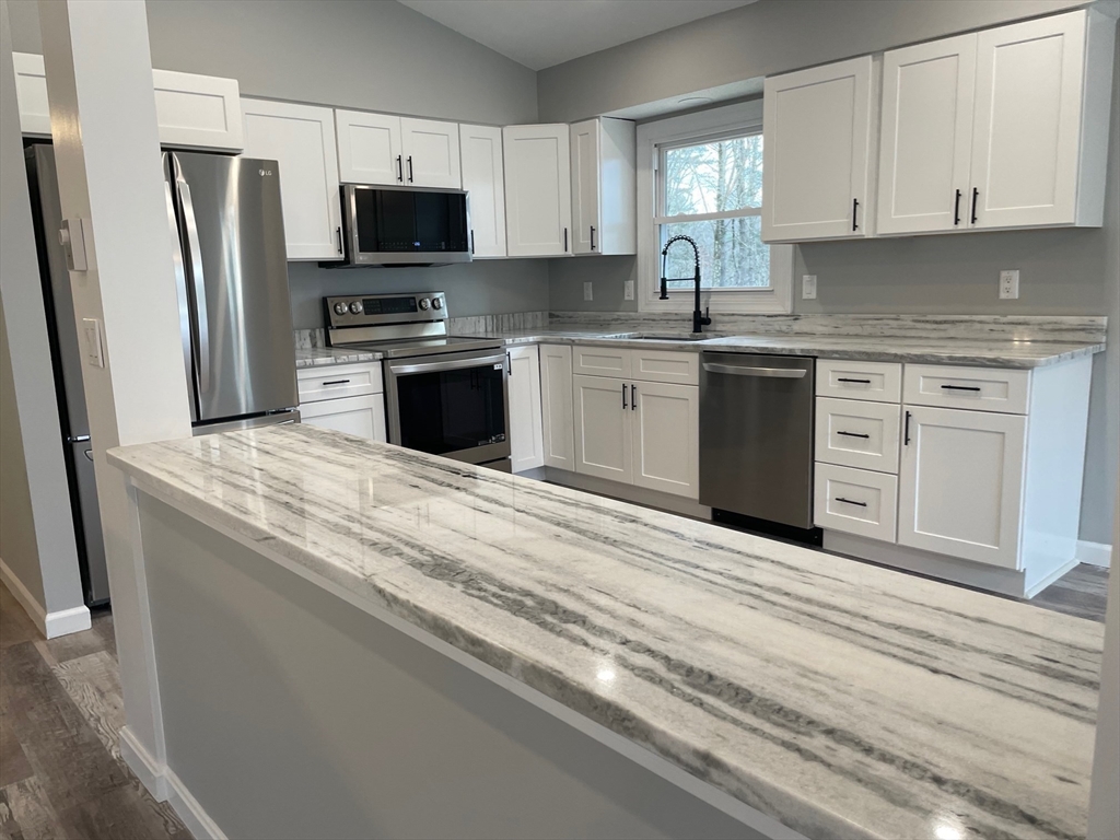 564 West Pelham Road Shutesbury, MA 01072 - Photo 10 of 40 a kitchen with granite countertop a sink stainless steel appliances and white cabinets