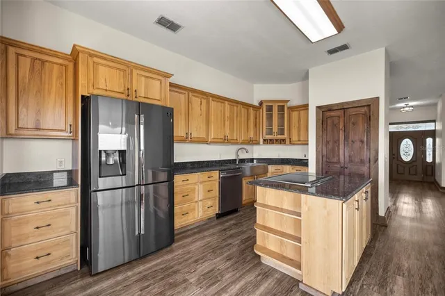 a kitchen with stainless steel appliances granite countertop a refrigerator stove and wooden cabinets