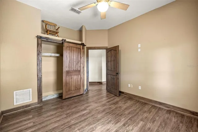 an empty room with wooden floor cabinet and windows