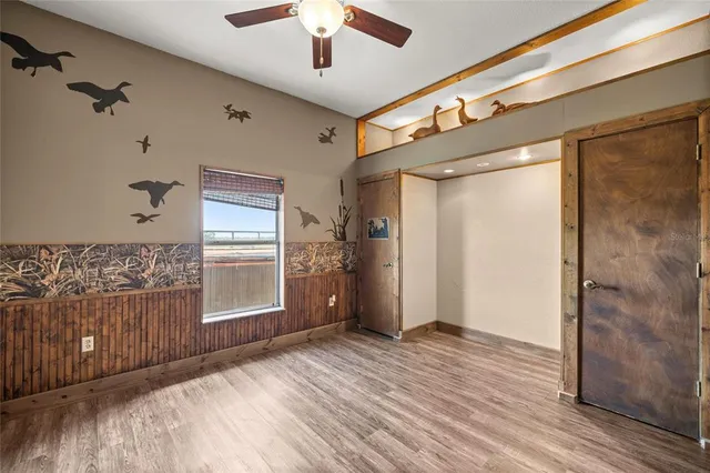 an empty room with wooden floor cabinet and windows