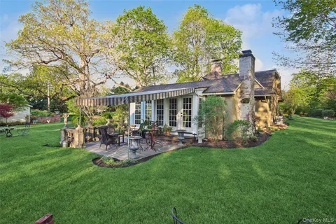 a view of a backyard with table and chairs potted plants and a large tree