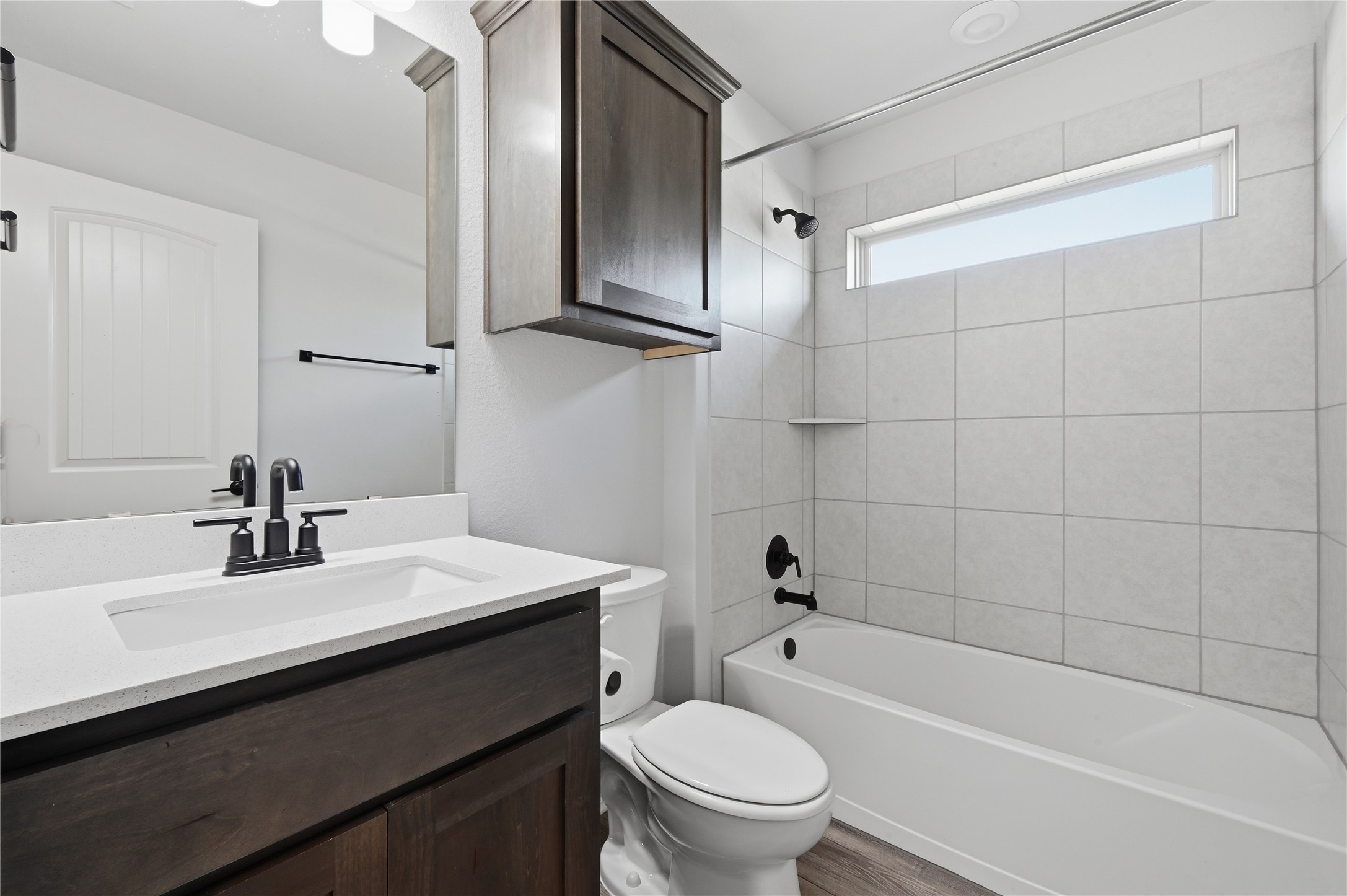 426 Cold Riv Run Kyle, TX 78640 - Photo 26 of 34 A well-appointed bathroom features a dark wood vanity, white quartz countertop, and a shower-over-tub with light gray tile surround.