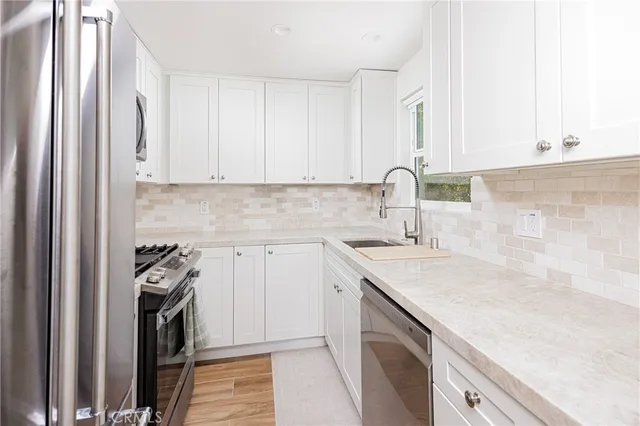 a kitchen with a sink dishwasher and a stove top oven with wooden floor