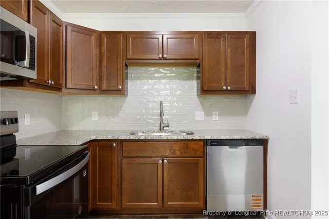 a kitchen with kitchen island granite countertop a sink cabinets and stainless steel appliances