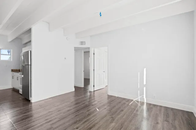 a view of an empty room with wooden floor and a sink