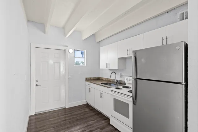 a kitchen with stainless steel appliances a refrigerator a sink and white cabinets