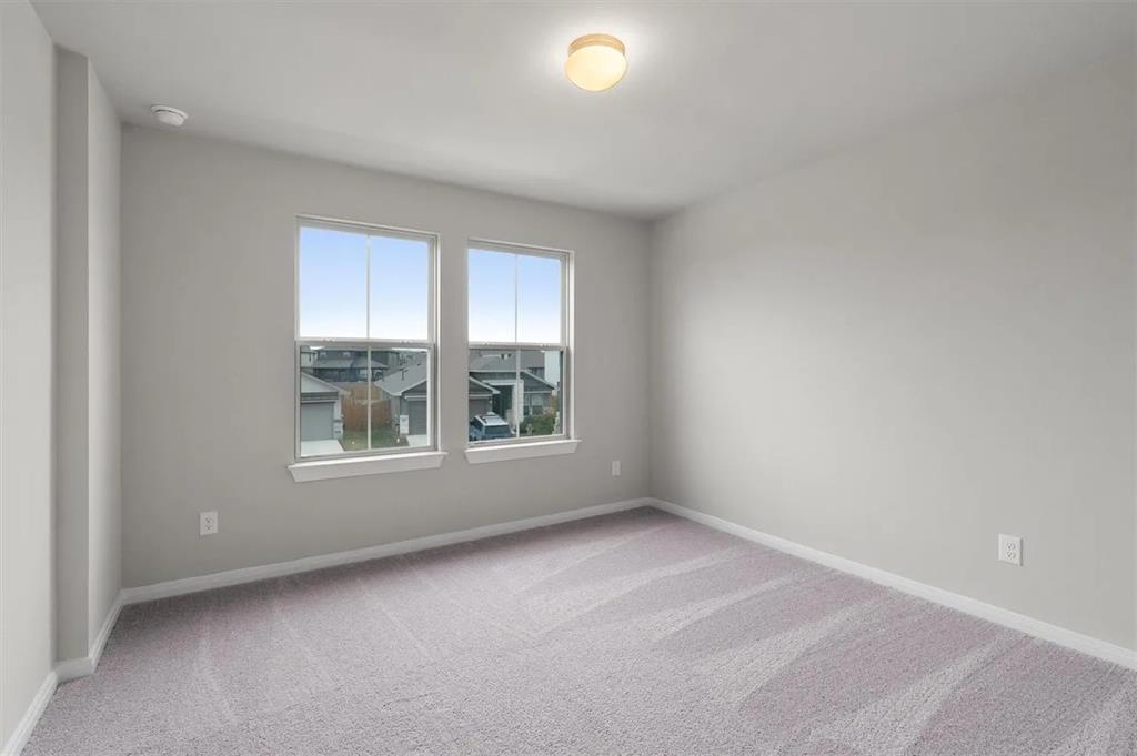 332 Stellar Wind Drive Georgetown, TX 78628 - Photo 24 of 29 A well-lit bedroom with fresh, neutral tones and a soft, patterned carpet.