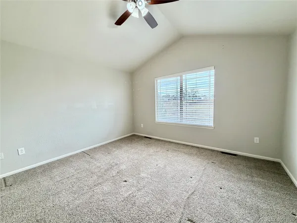 an empty room with a ceiling fan and window