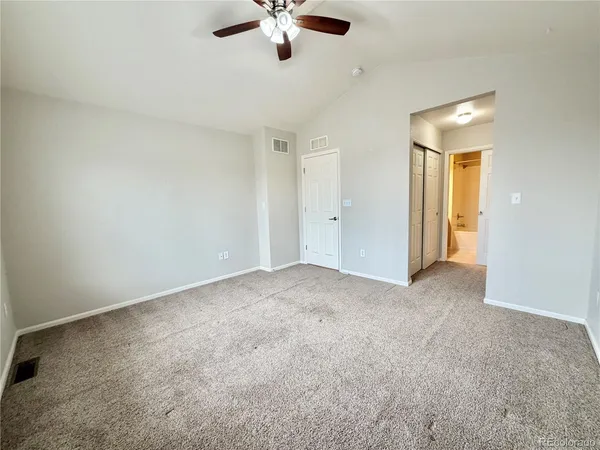 an empty room with chandelier fan and windows