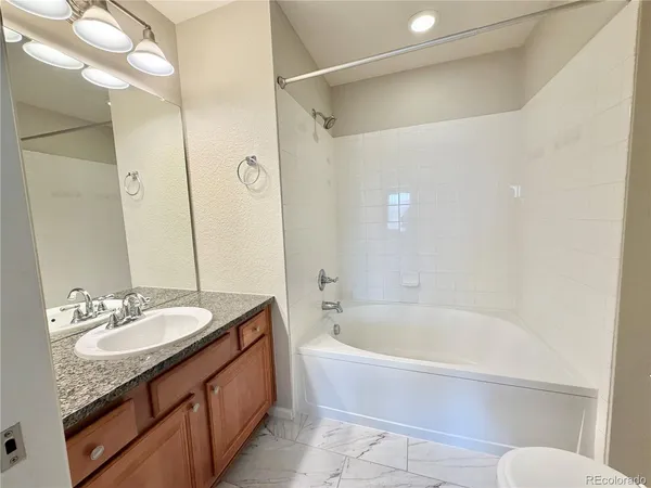 a bathroom with a granite countertop tub sink and mirror