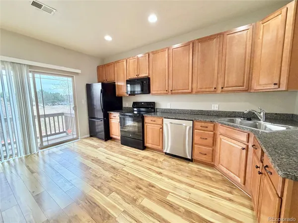 a kitchen with stainless steel appliances granite countertop a stove a sink dishwasher a refrigerator and a microwave oven with wooden floor