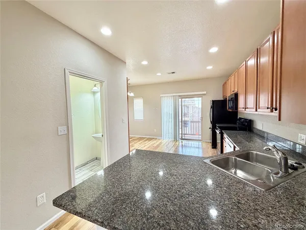 a view of a kitchen with stainless steel appliances granite countertop a sink refrigerator and microwave
