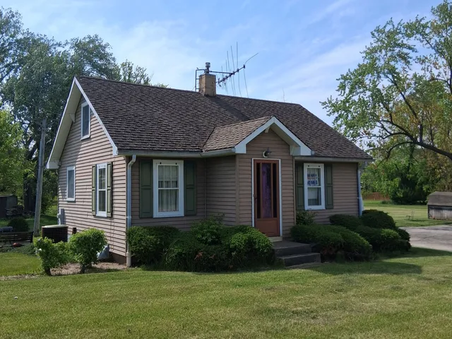 a view of a house with a yard plants and large tree