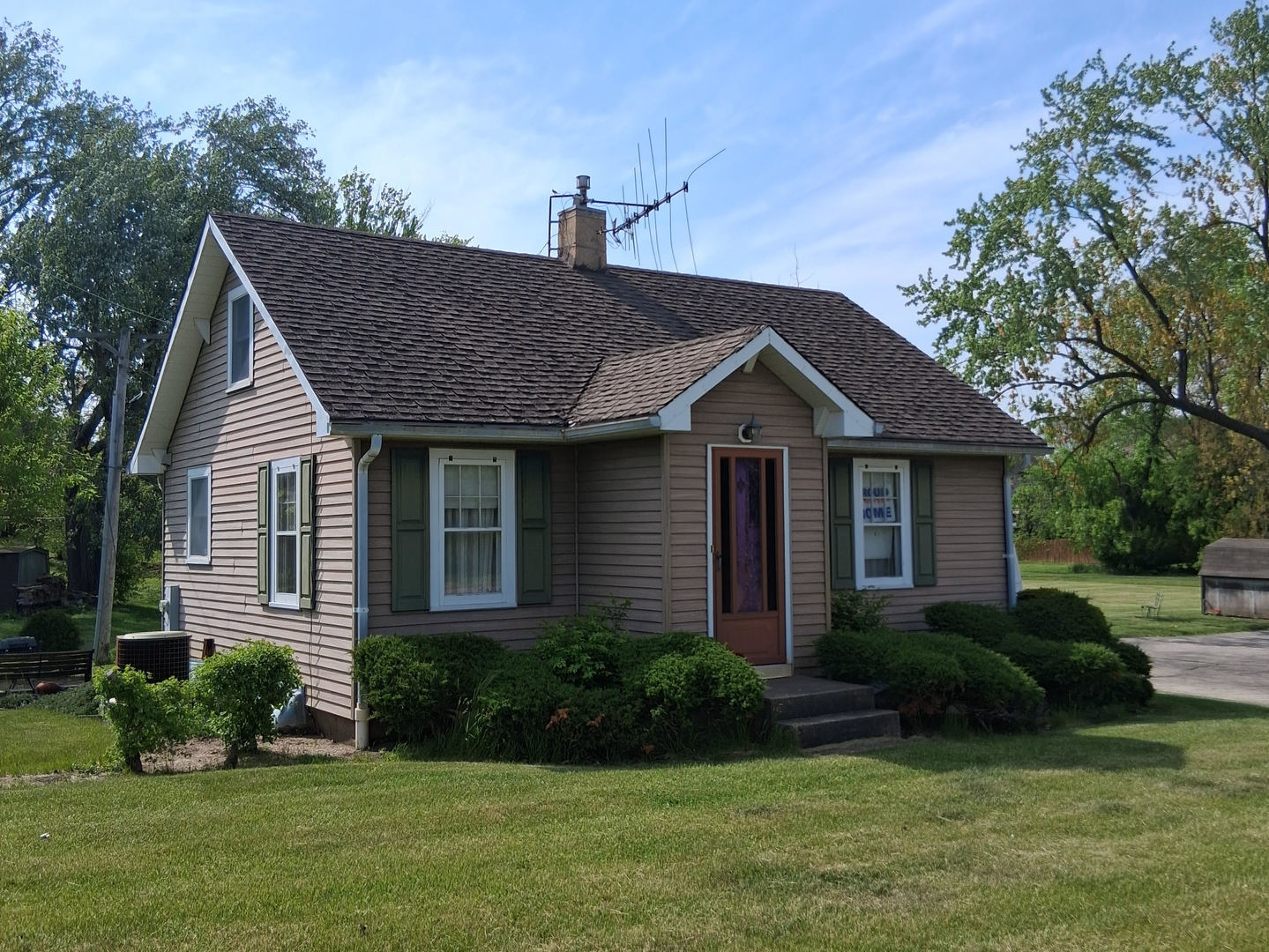 a view of a house with a yard plants and large tree